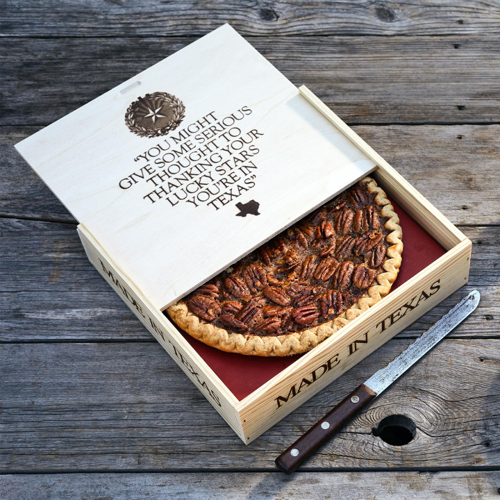 Close-up image of pecan pie gift box partially opened with a serving knife at the box base