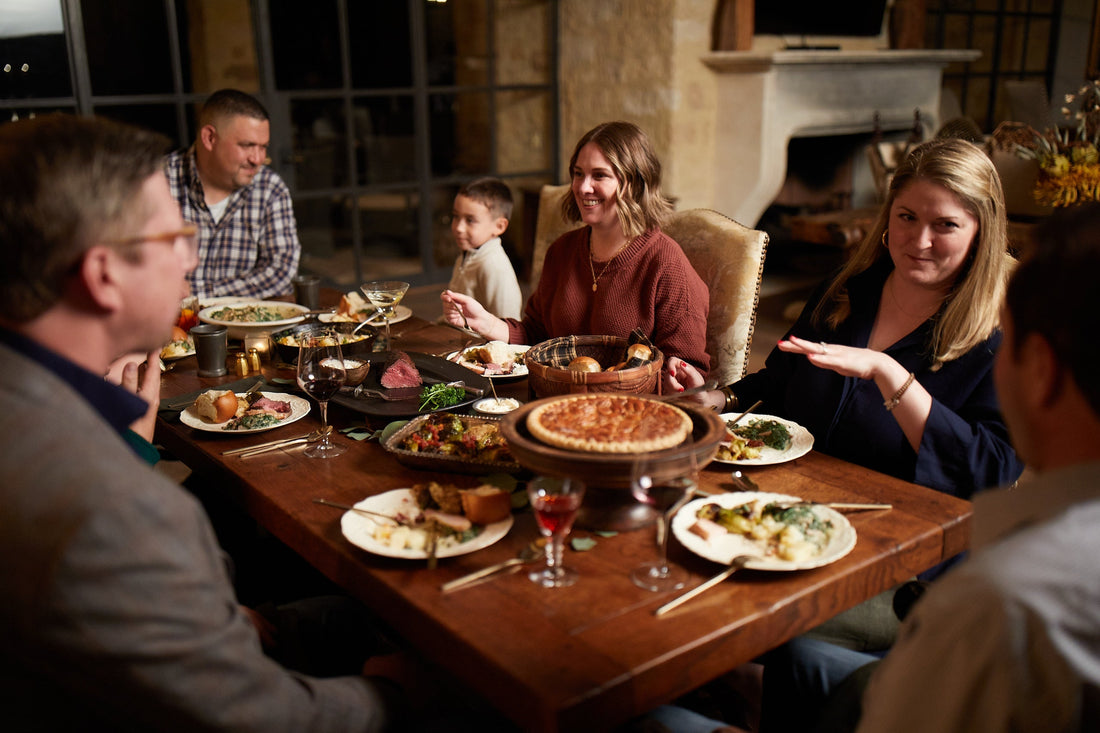 Family and friends gathered around a holiday table enjoying Goode Co. BBQ food.