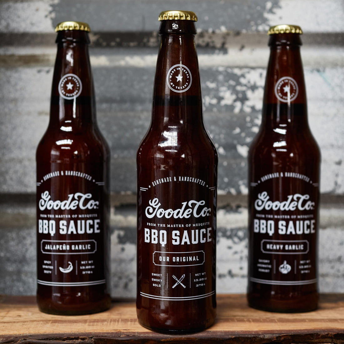 Close-up of the three bottles of Goode Co. BBQ sauce with the original bottle at the forefront.