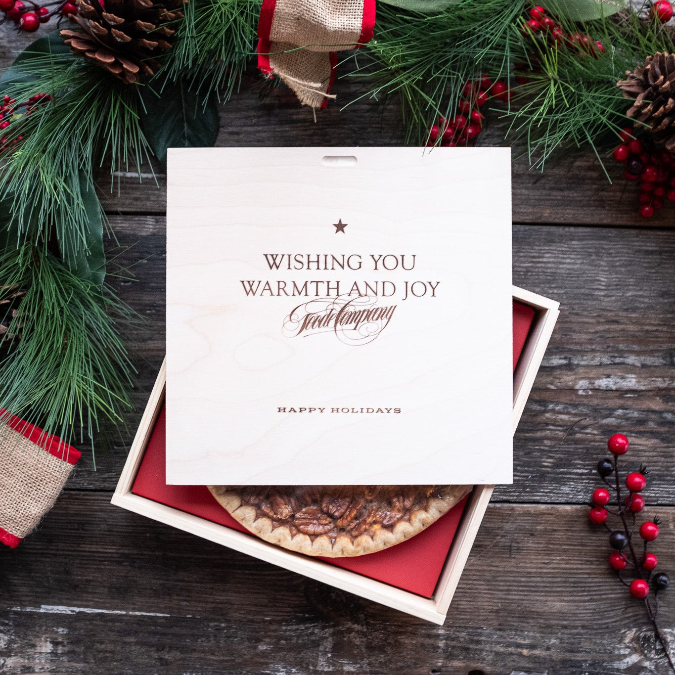 Wooden gift box with pecan pie on wooden surface adorned with holiday garland