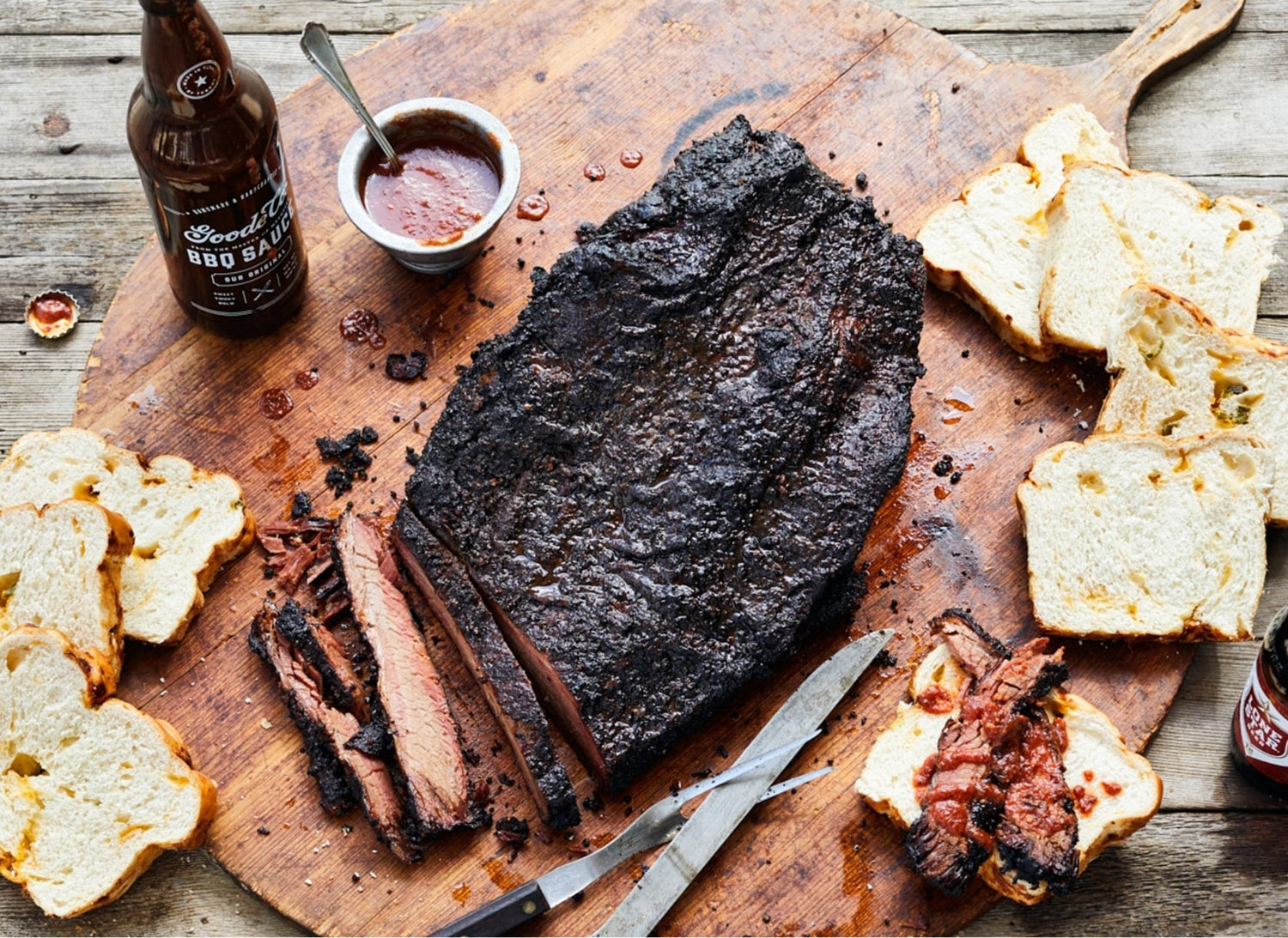 Smoked Mesquite Brisket on Wooden Cutting Board with Goode Co. BBQ Sauce